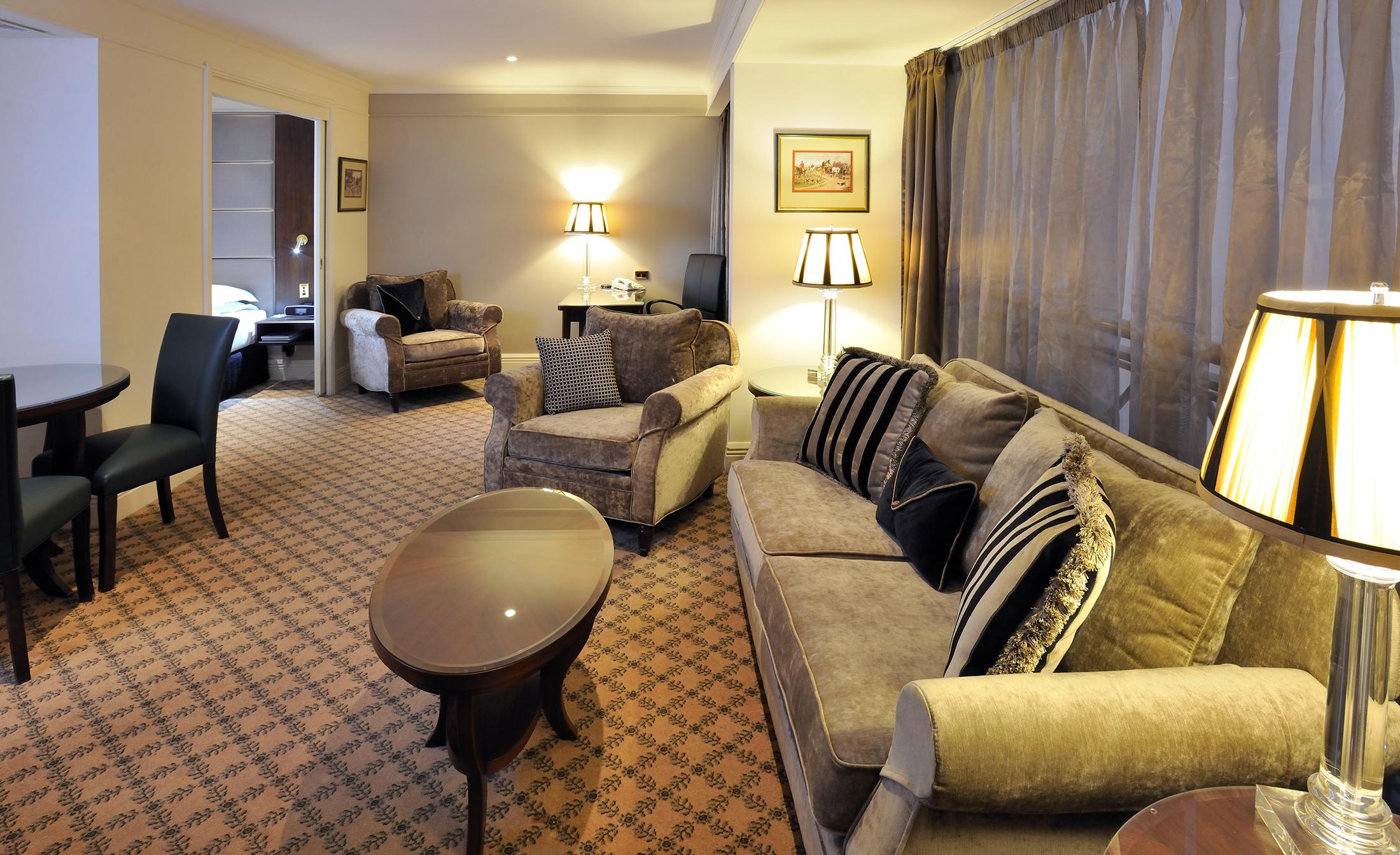 Stamford Plaza Melbourne Hotel Eksteriør billede The photo shows a stylish and comfortable living area. It features plush seating, including a sofa with decorative cushions and a couple of armchairs. There's a circular coffee table in the center of the seating arrangement. The room has soft lightin