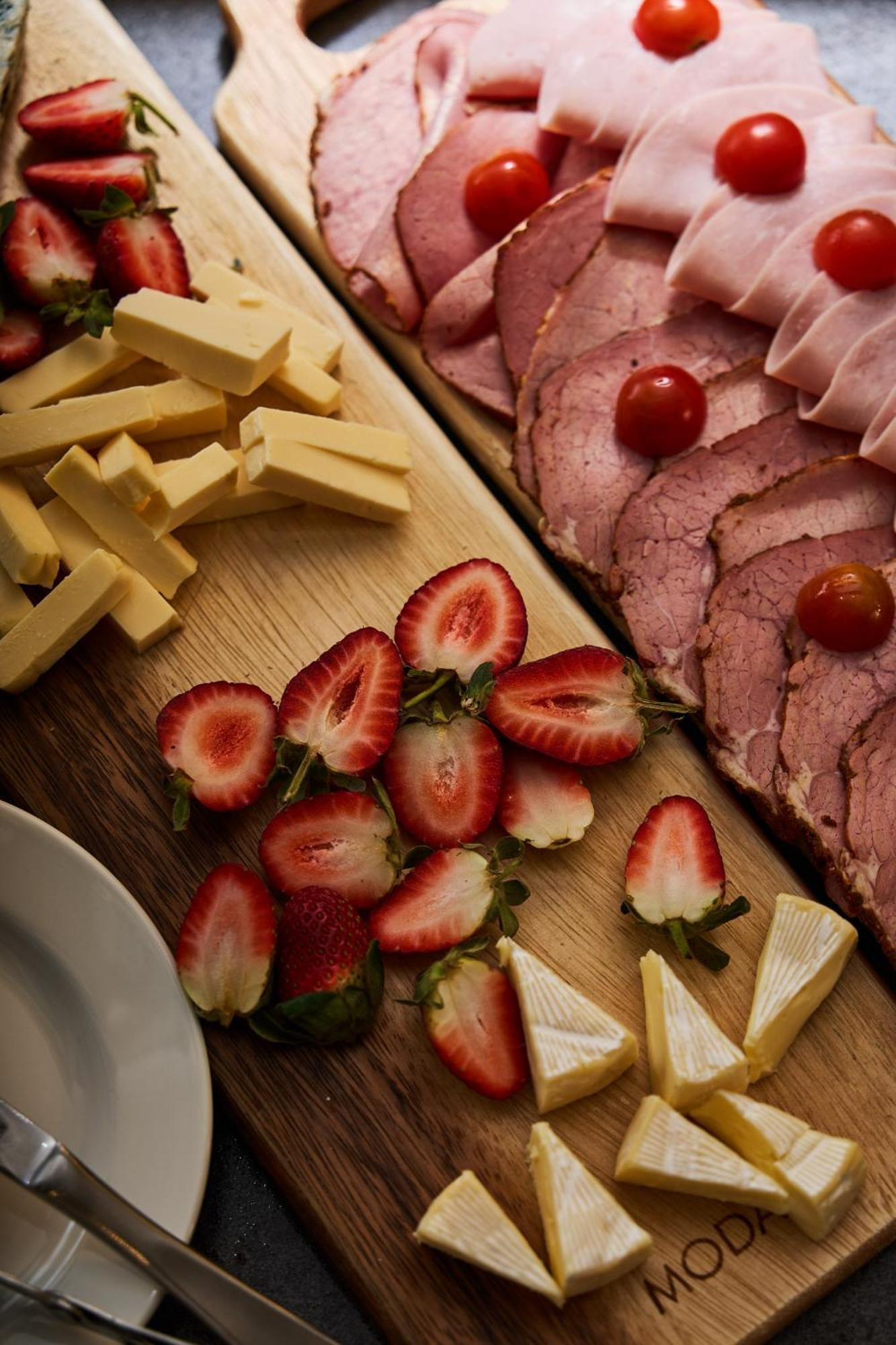 Stamford Plaza Melbourne Hotel Eksteriør billede The photo displays an assortment of food items arranged on a wooden surface. There are slices of various meats, including ham, alongside round cherry tomatoes. Next to the meat, there are several pieces of yellow cheese cut into sticks. Additionally,
