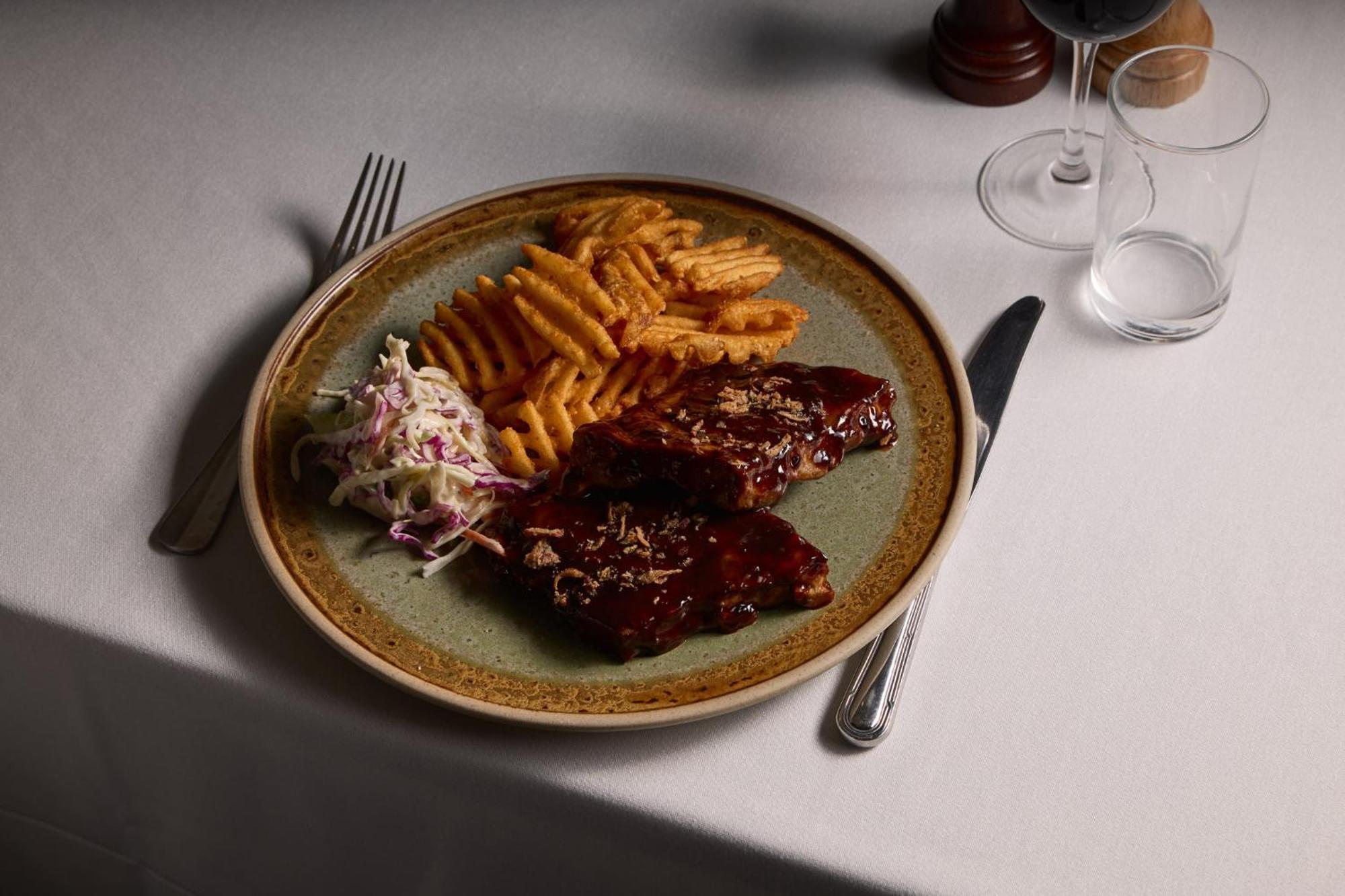 Stamford Plaza Melbourne Hotel Eksteriør billede The photo displays a plate of food featuring two pieces of steak that appear to be glazed with a rich sauce. Alongside the steak, there are crinkle-cut fries arranged neatly on one side of the plate. Additionally, there's a small serving of coleslaw,