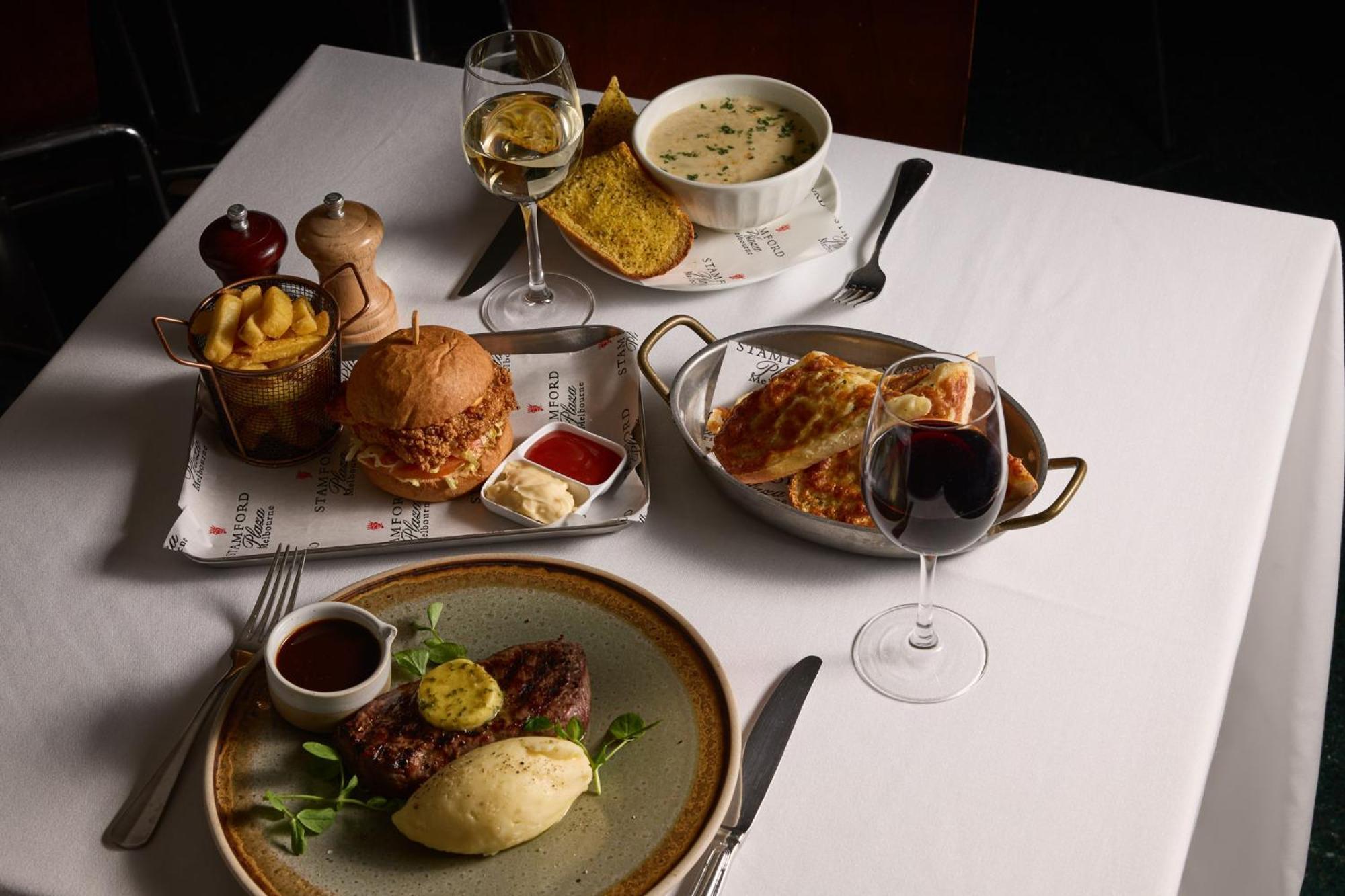 Stamford Plaza Melbourne Hotel Eksteriør billede The photo showcases a variety of food and drinks arranged on a table set with a white tablecloth. 

1. **Main Dish:** A plate features a portion of steak topped with a slice of butter, accompanied by mashed potatoes and a garnish of greenery.
2. **Bu