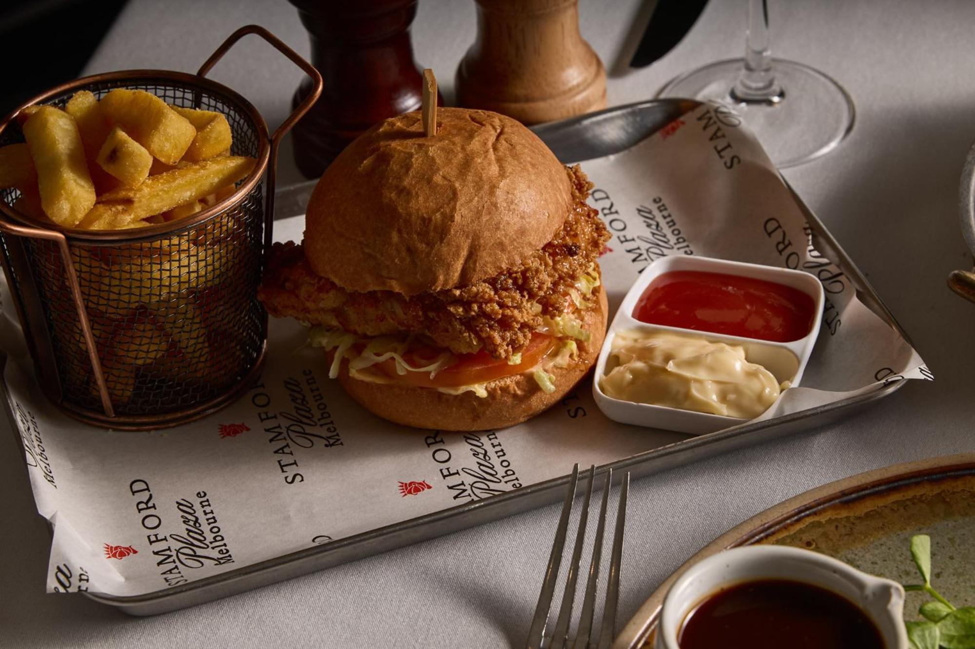 Stamford Plaza Melbourne Hotel Eksteriør billede The photo features a meal served on a tray. In the center is a sandwich made with a golden-brown chicken fillet that appears crispy, placed inside a soft bun. The sandwich is likely complemented by some type of sauce or condiments underneath the chic