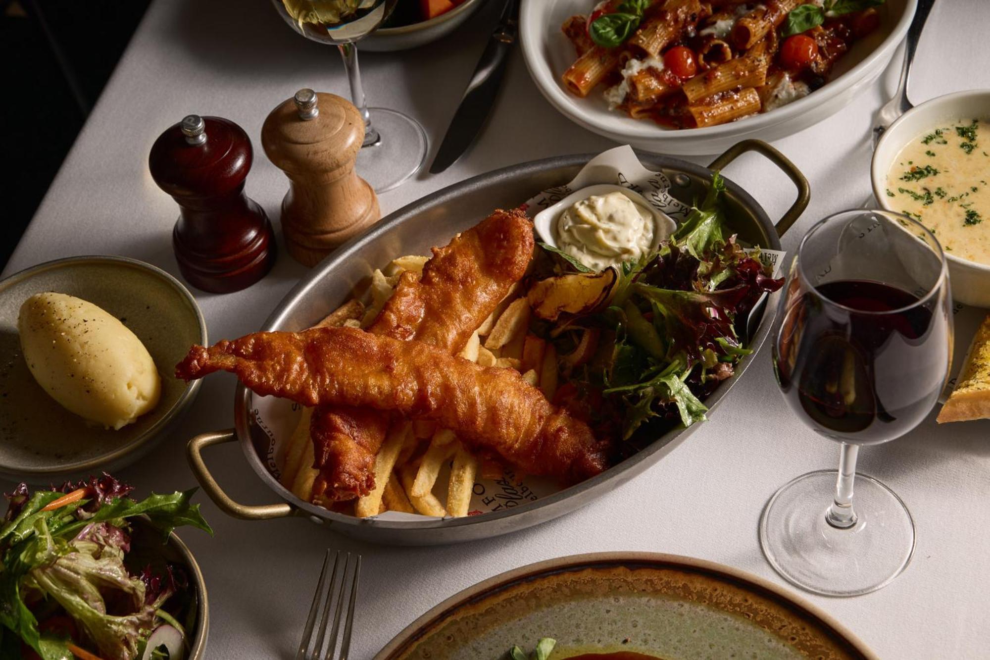 Stamford Plaza Melbourne Hotel Eksteriør billede The photo showcases a beautifully arranged meal. In the foreground, there are two pieces of golden-battered fish served with crispy fries. Accompanying the fish is a small dollop of creamy sauce and a side salad, which has a mix of greens. Surroundin